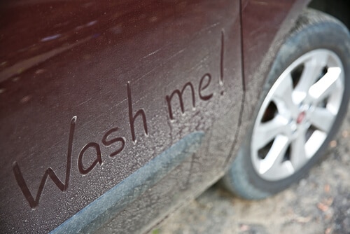 The words "Wash me" written on dirty car