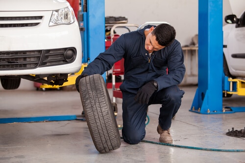Mechanic inspects a worn tire's tread