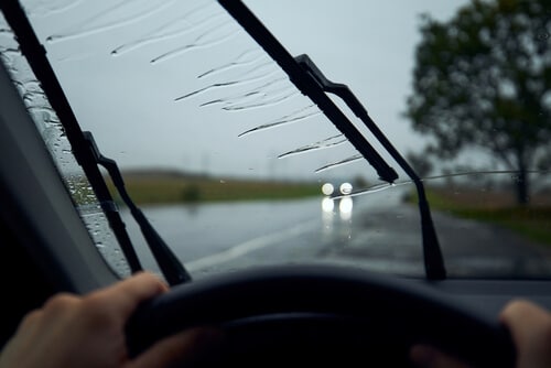 Windshield wipers on a rainy day with headlights from another driver